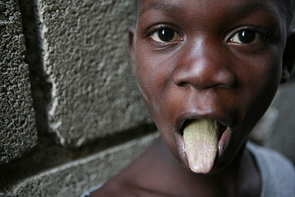 haitian child shows his tongue after eating dirt cookies - his meal for the day